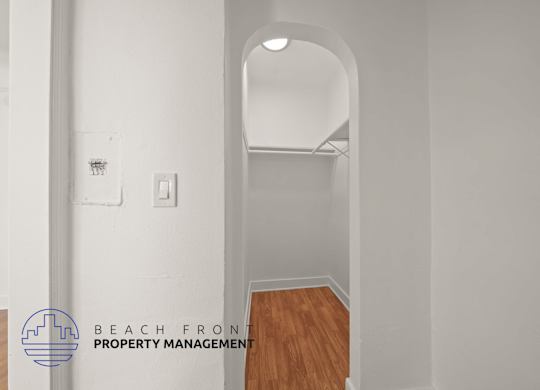 A white hallway with a wooden floor and a logo for Beach Front Property Management.