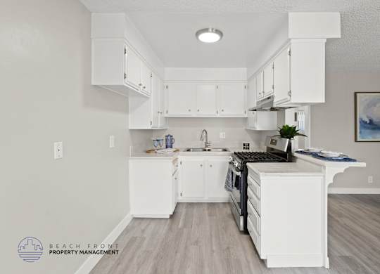 A kitchen with white cabinets and a wooden floor.
