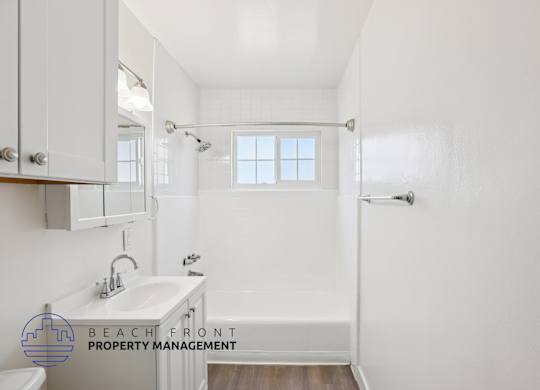 A white bathroom with a sink, mirror, and bathtub.