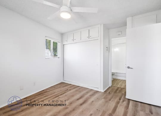 A room with a ceiling fan and wooden flooring.