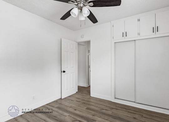 A room with a ceiling fan and wooden flooring.