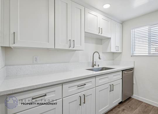 A kitchen with white cabinets and a sink.