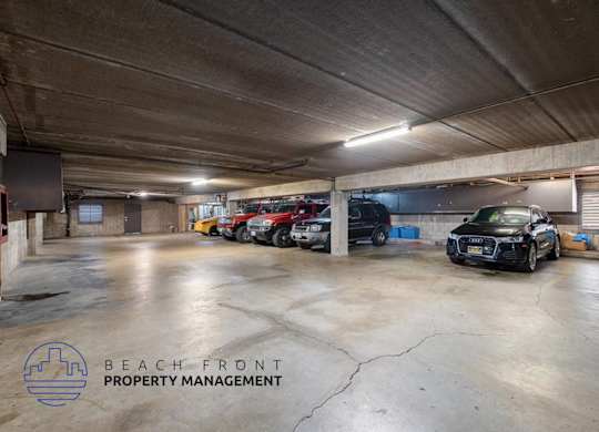 A black car is parked in a large, empty parking garage.