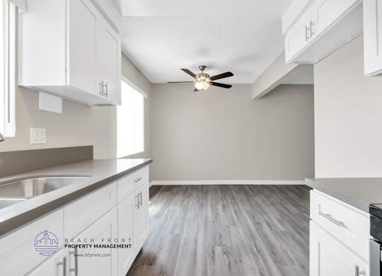 A kitchen with white cabinets and a ceiling fan.