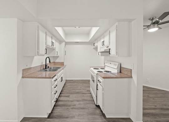 A kitchen with white cabinets and a wooden floor.