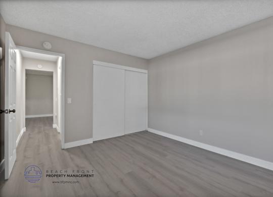A room with a door on the left and a white closet on the right.