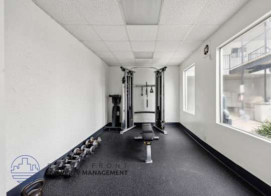 A gym with a row of dumbbells and a weight rack.