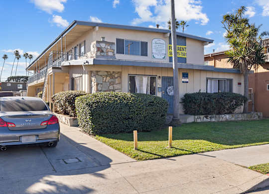 A residential building with a car parked in front.