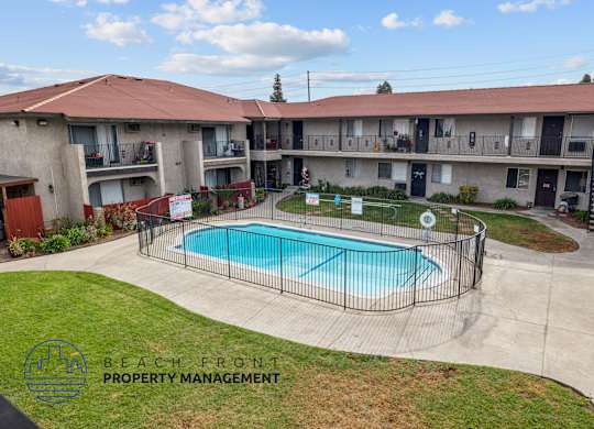 A swimming pool is surrounded by a fence in a courtyard.
