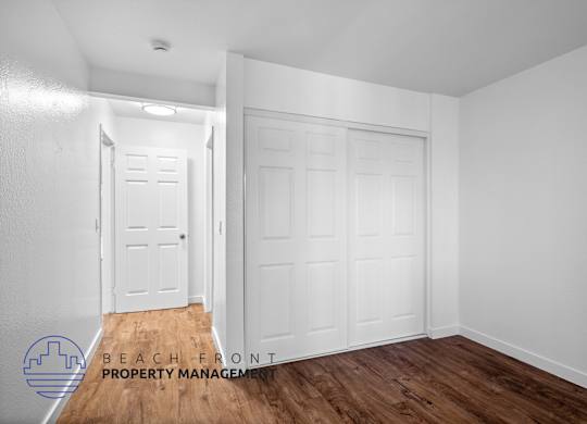 A room with two white doors and a logo for Beach Front Property Management.