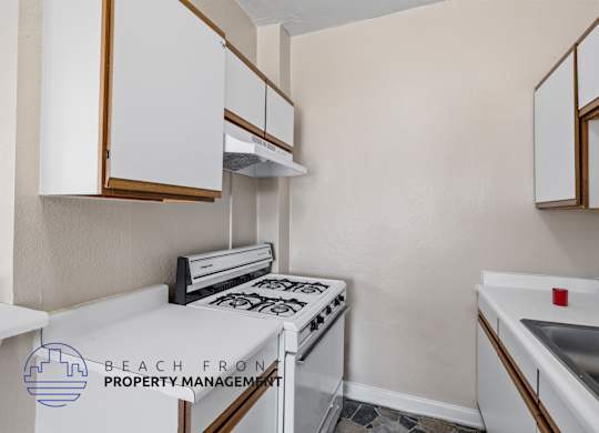 A kitchen with white cabinets and a stove top oven.