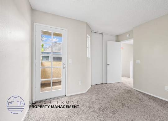A room with a carpeted floor and a window with a view of a house.