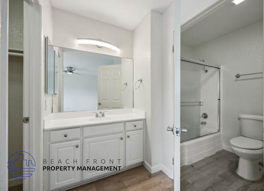 A bathroom with a white toilet and a white sink with a mirror above it.