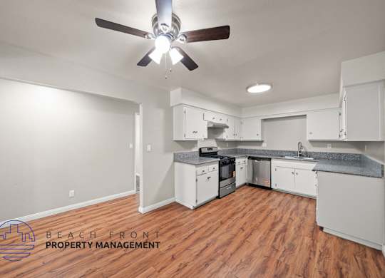 A kitchen with a ceiling fan and wooden floors.