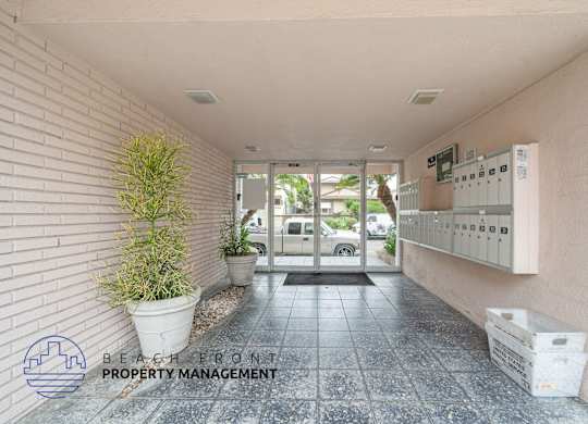 A hallway with a plant and a sign for Beach Front Property Management.