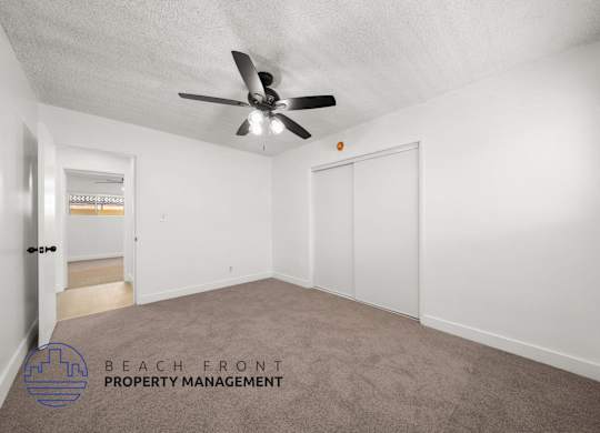 A room with a ceiling fan and a carpeted floor.