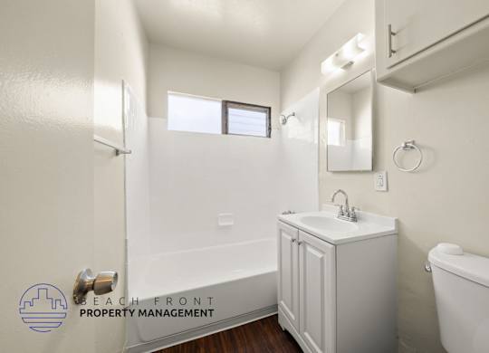 A white bathroom with a sink, mirror, and bathtub.