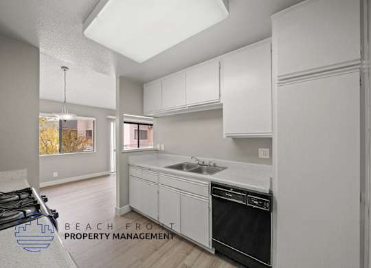 a white kitchen with white cabinets and a black dishwasher