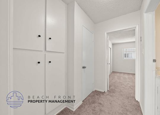 A hallway with white doors and a logo for Beach Front Property Management.