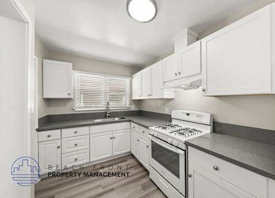 A kitchen with white cabinets and a stove top oven.