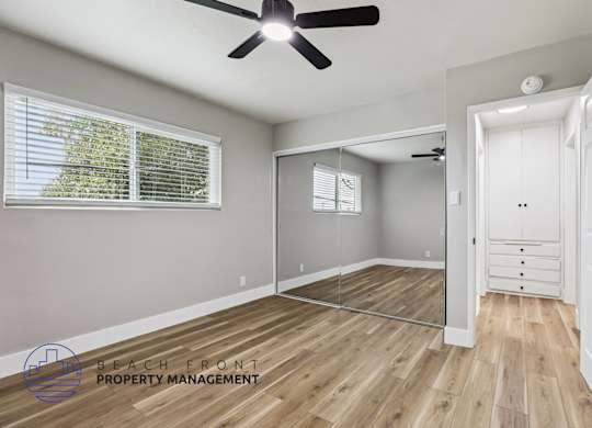 A room with a ceiling fan and wooden flooring.