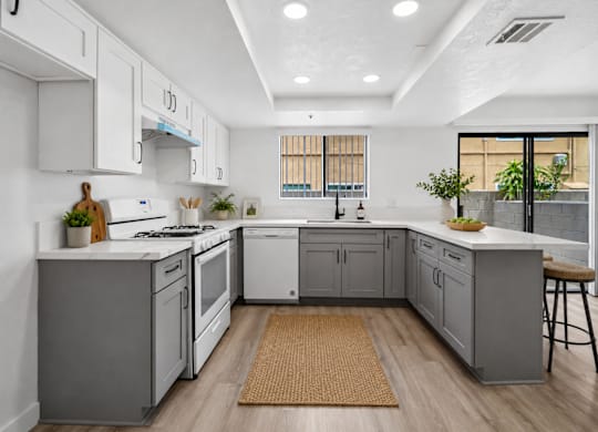 A modern kitchen with white cabinets and a wooden floor.