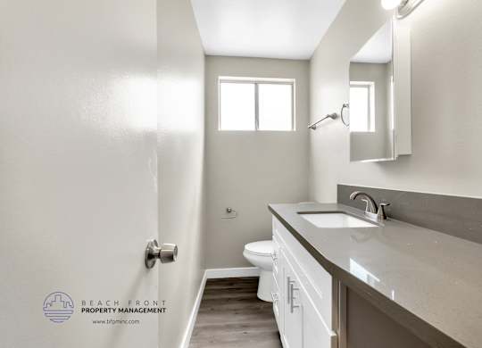 A bathroom with a toilet, sink, and mirror.