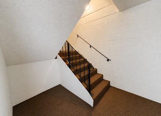 A staircase with a metal railing and a light on the wall.