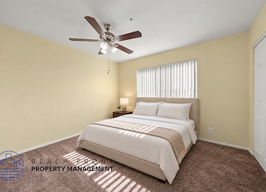 A bedroom with a bed, carpet, and a ceiling fan.