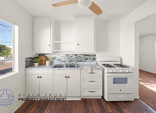 A kitchen with white cabinets and a wooden floor.
