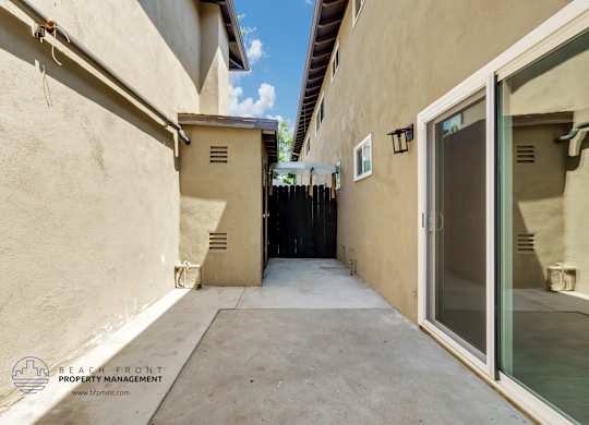 A narrow alleyway between two buildings with a clear blue sky above.