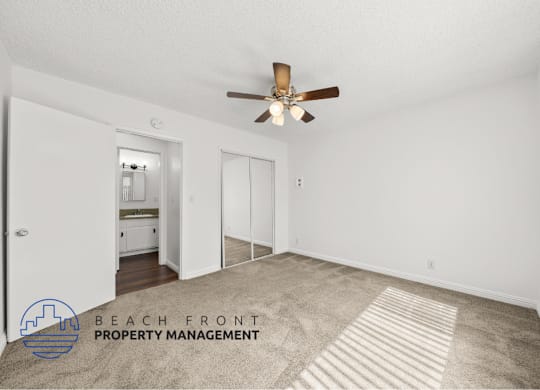 view of a large bedroom with mirror doors for the closet and leads into the bathroom