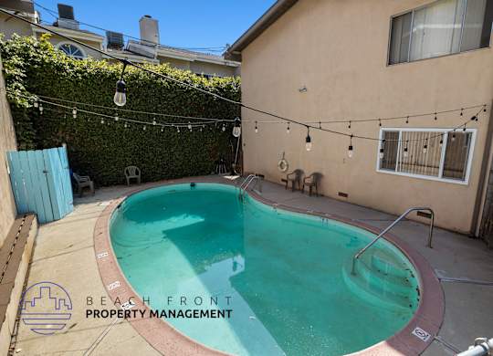 a backyard swimming pool with a building and a chain link fence