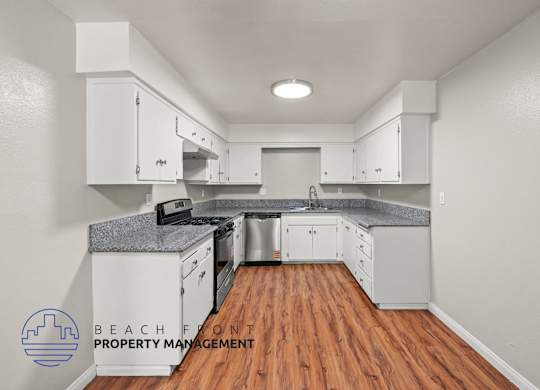 A kitchen with wooden floors and white cabinets.