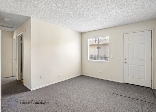 A sparsely furnished room with a window and a door.