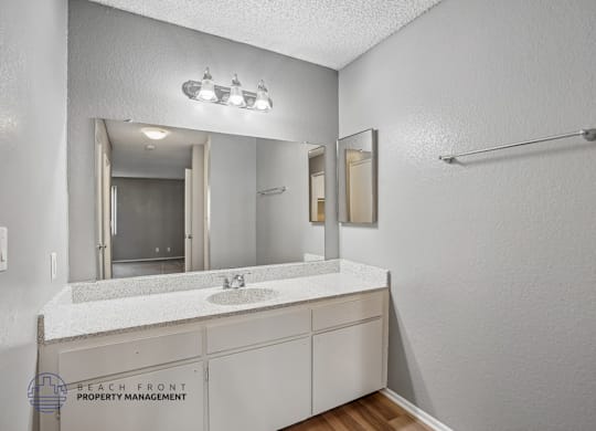 A bathroom with a white countertop and a large mirror.