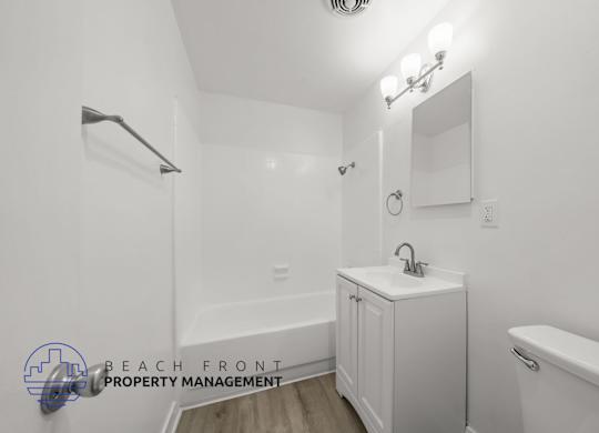 A white bathroom with a sink, mirror, and bathtub.