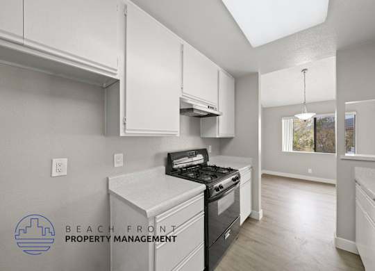 a kitchen with white cabinets and a stove and a window