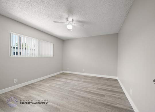 A room with a ceiling fan and a window with blinds.