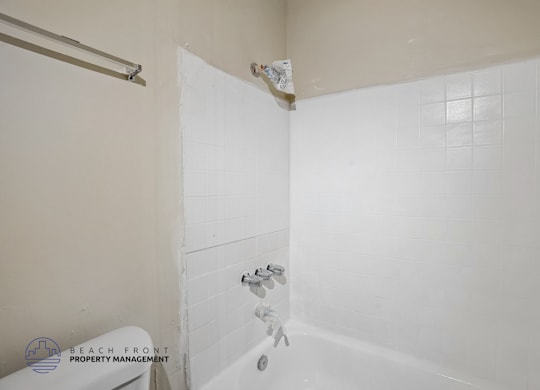 A bathroom with a white tub and shower head.