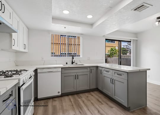 A kitchen with white and grey cabinets and a wooden floor.