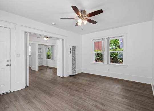 A room with a ceiling fan and wooden flooring.