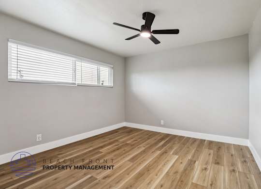 A room with a ceiling fan and wooden flooring.
