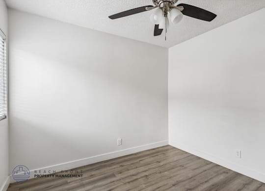 A room with a ceiling fan and wooden flooring.
