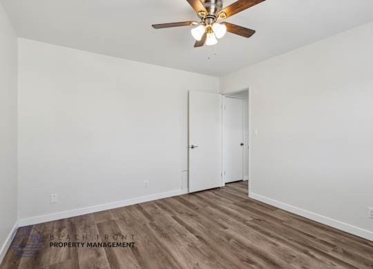 A room with a ceiling fan and wooden flooring.