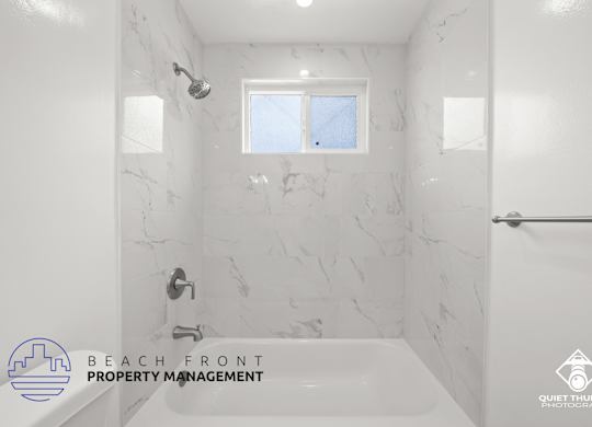 a white bathroom with a tub and a shower and a window