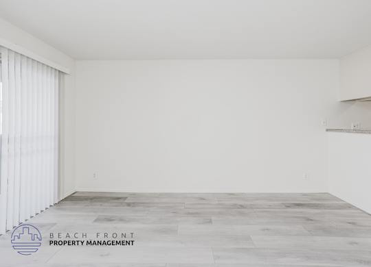 A spacious room with a wooden floor and white walls.