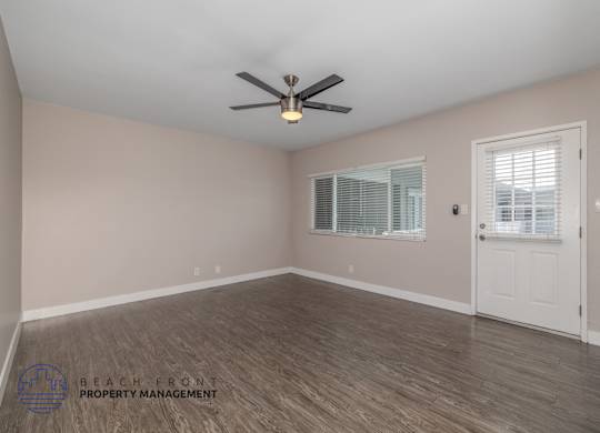 A room with a ceiling fan and wooden flooring.
