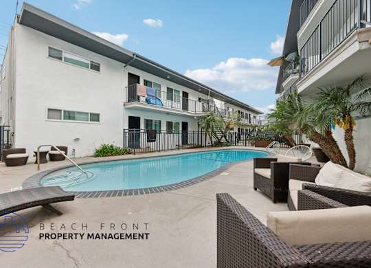 A pool area with lounge chairs and a building in the background.