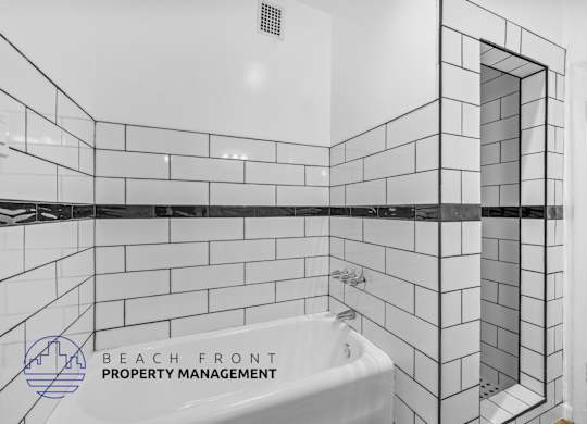 a white tiled bathroom with a tub and a shower